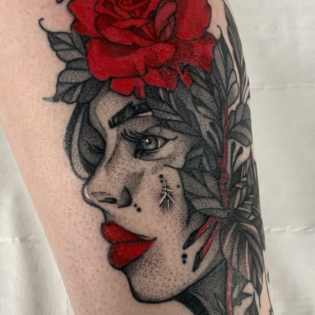 Dot work female face tattoo. With red lips and a red flower in the hair. Tattoo done at Area 51 Basingstoke