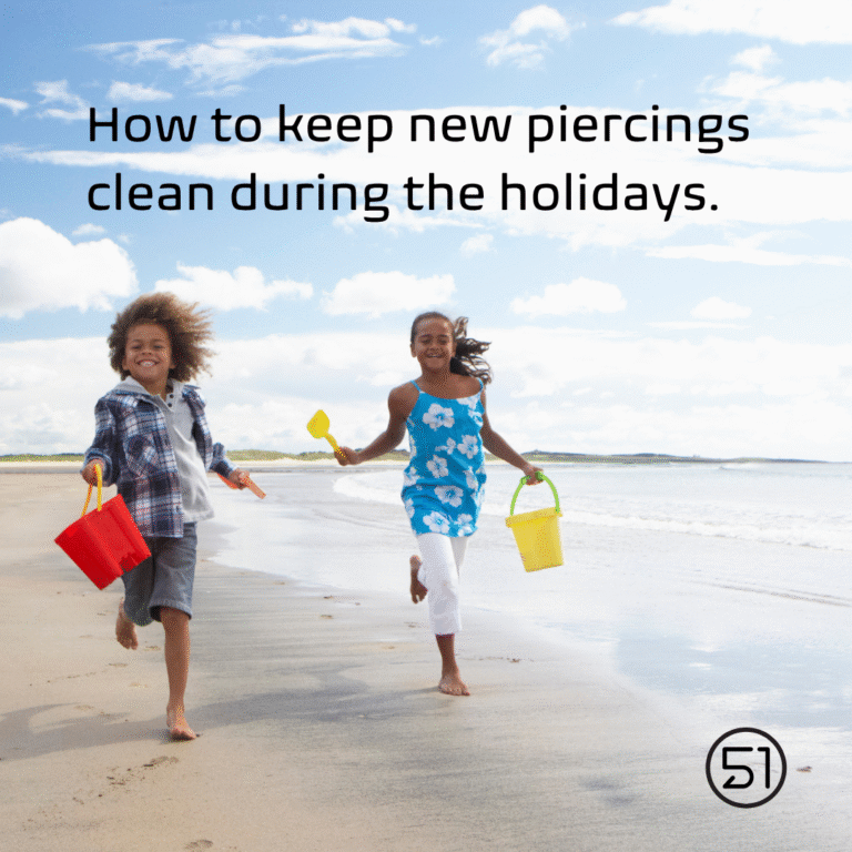 Image shows two children playing on the beach. Text reads "How to keep new piercings clean during the holidays"